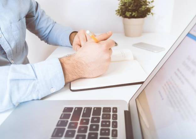 Neues Webdesign für einen besseren Webauftritt Mann, der am Computer arbeitet und sich Notizen aufschreibt